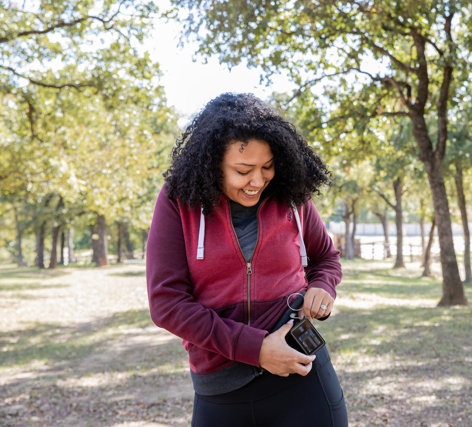 Young woman checks insulin pump and blood sugar monitor while hiking outdoors