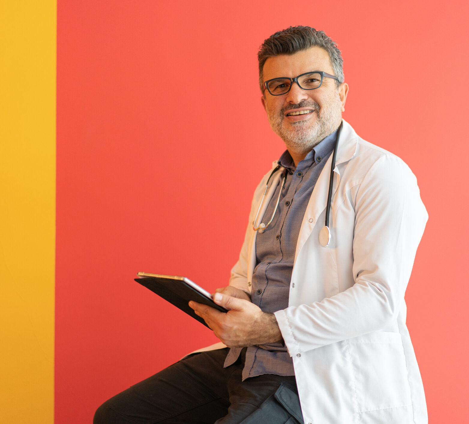 Doctor smiling with clipboard with a red background behind him, preparing to tell you about time in range