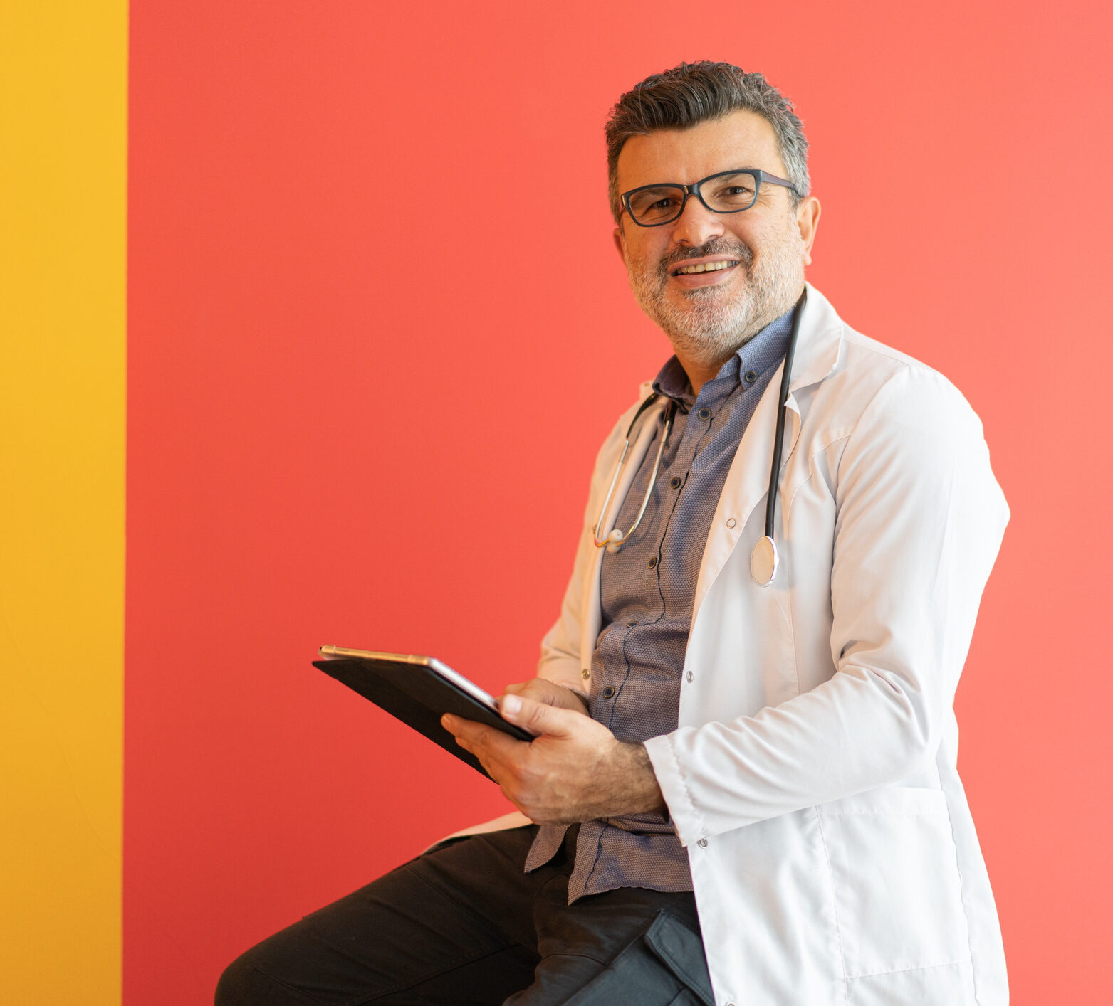 Doctor smiling with clipboard with a red background behind him, preparing to tell you about time in range