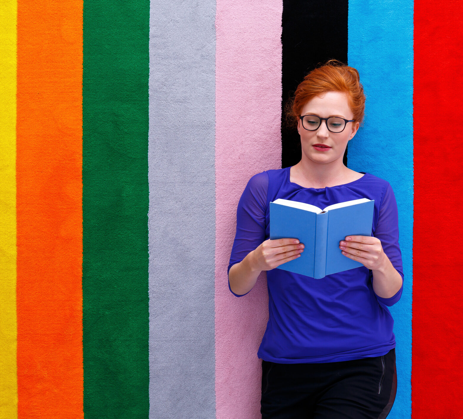 Woman reading all about time in range with a rainbow background behind her