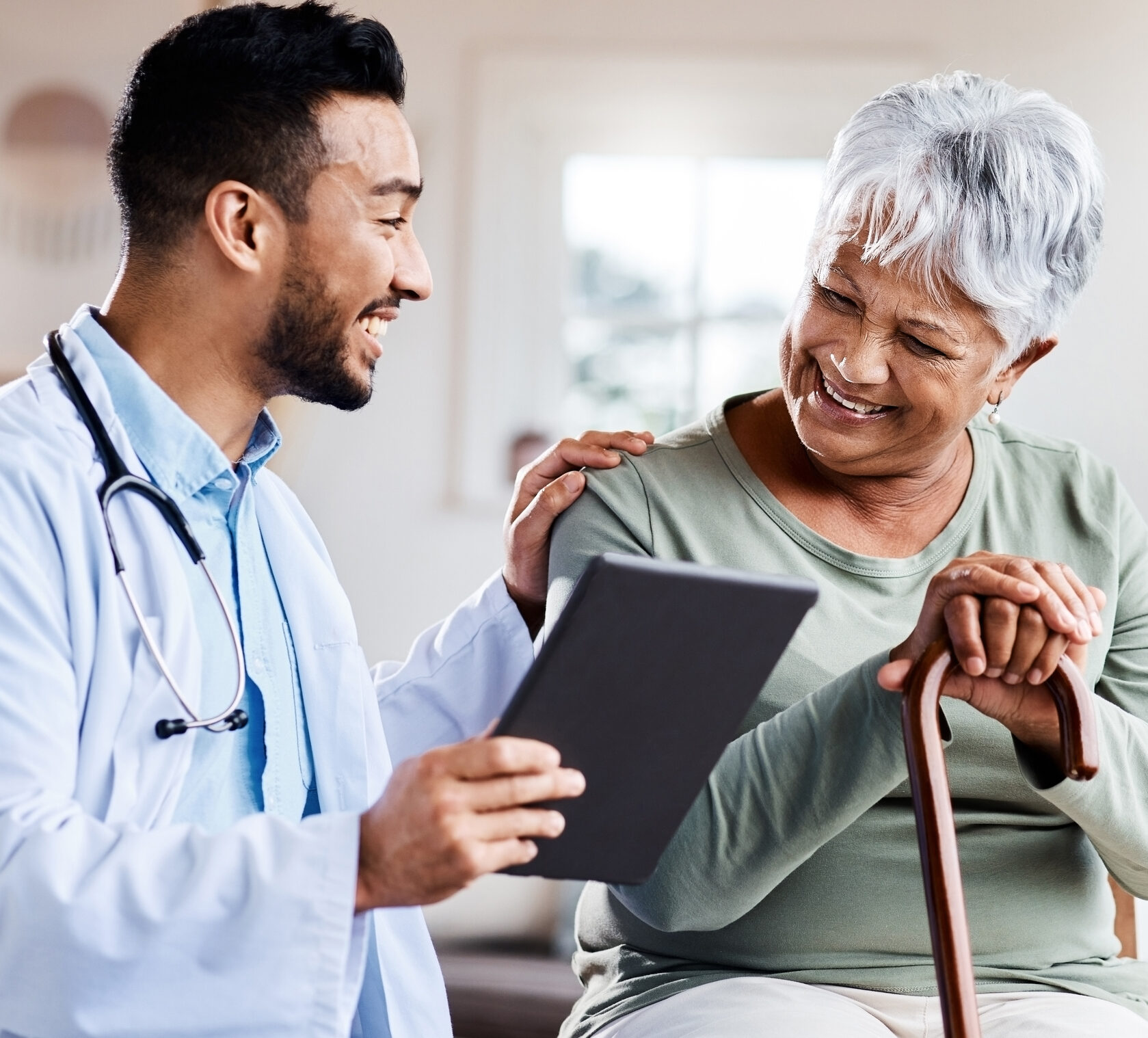 Male doctor supporting and smiling with older Latina woman, talking about how time in range can help her thrive with diabetes.