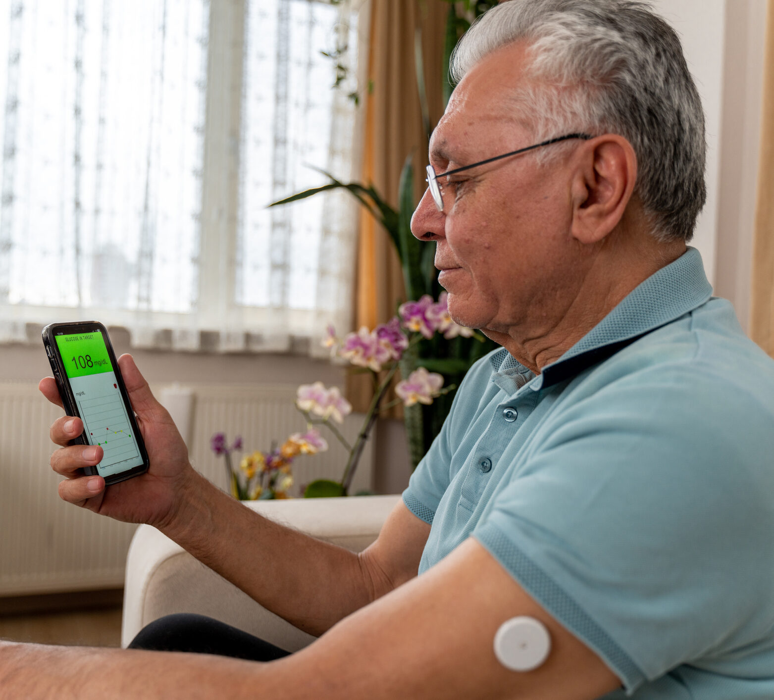 Man in blue shirt and glasses checking his glucose levels and time in range on his phone.
