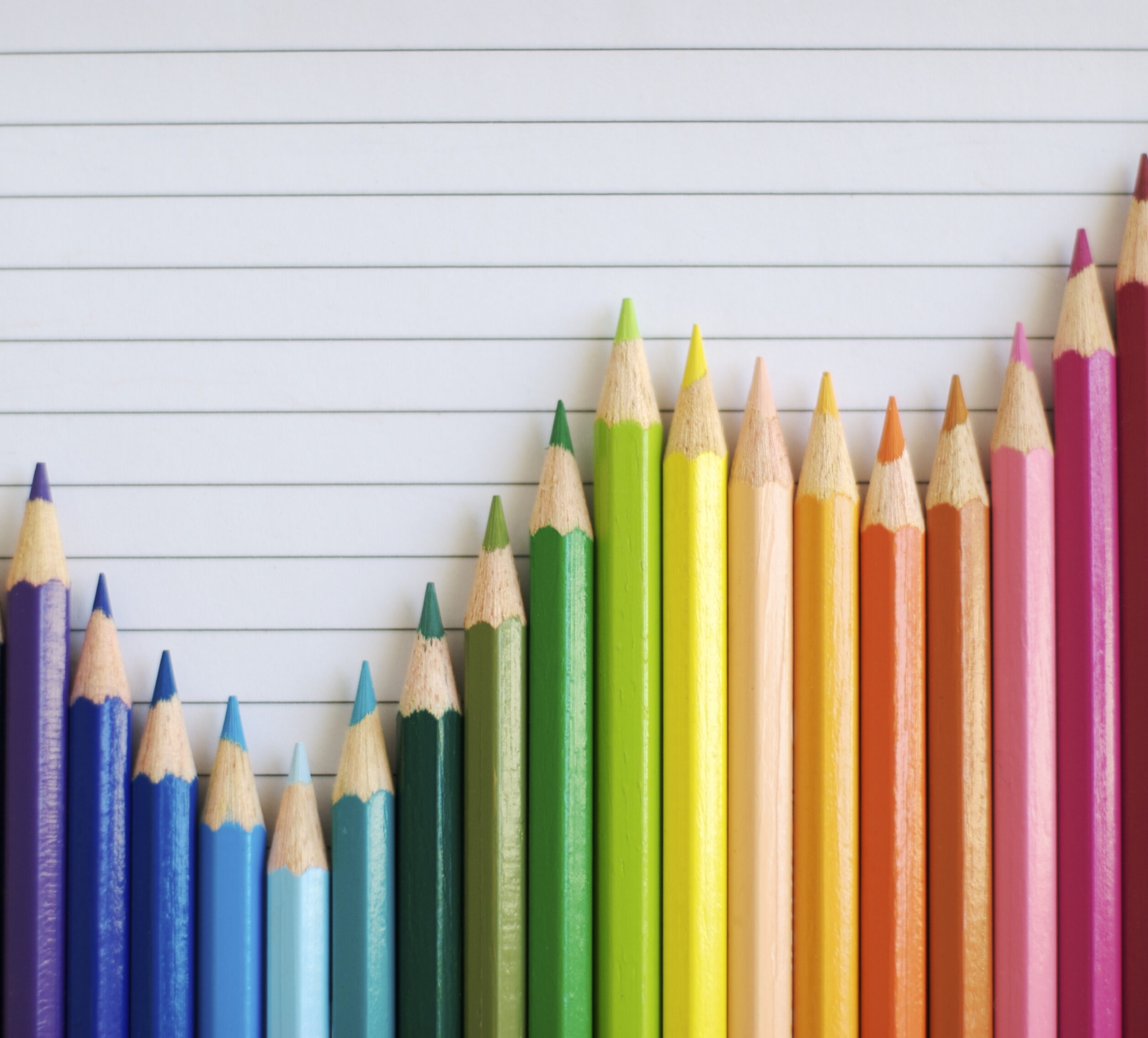 Colored pencils lined up to make a graph trending upwards