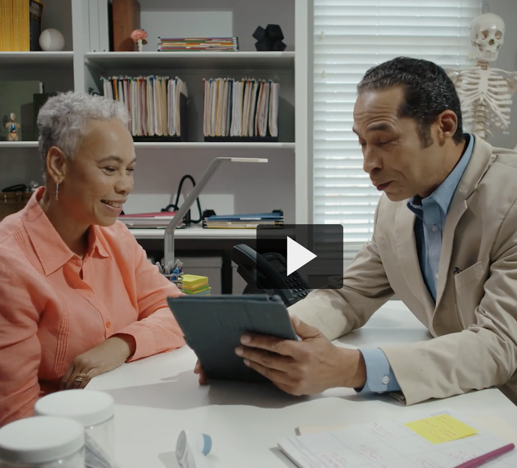 Dr and patient sitting down looking at an electronic tablet together (video clip screenshot)