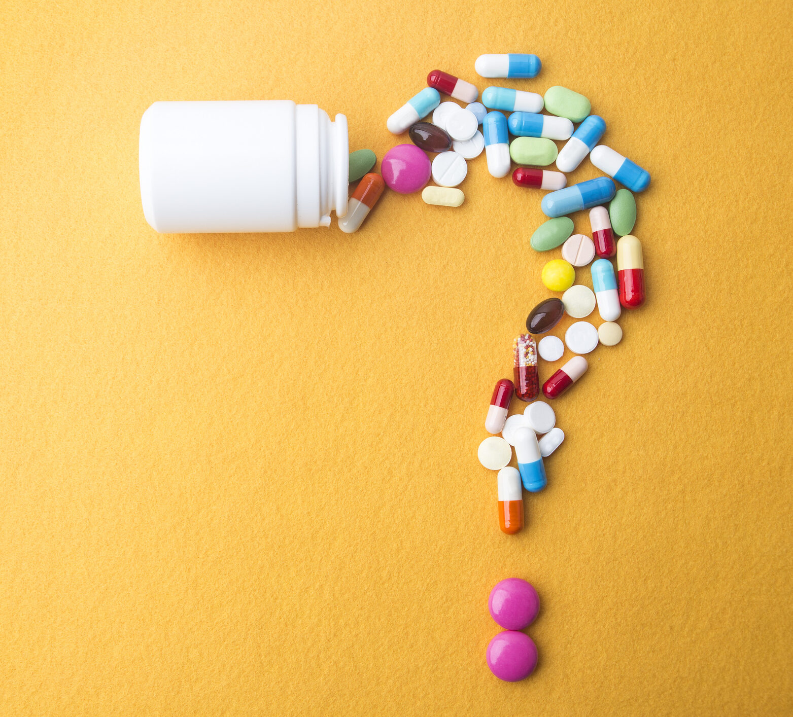 Pills or capsules as a question mark and white plastic bottle.