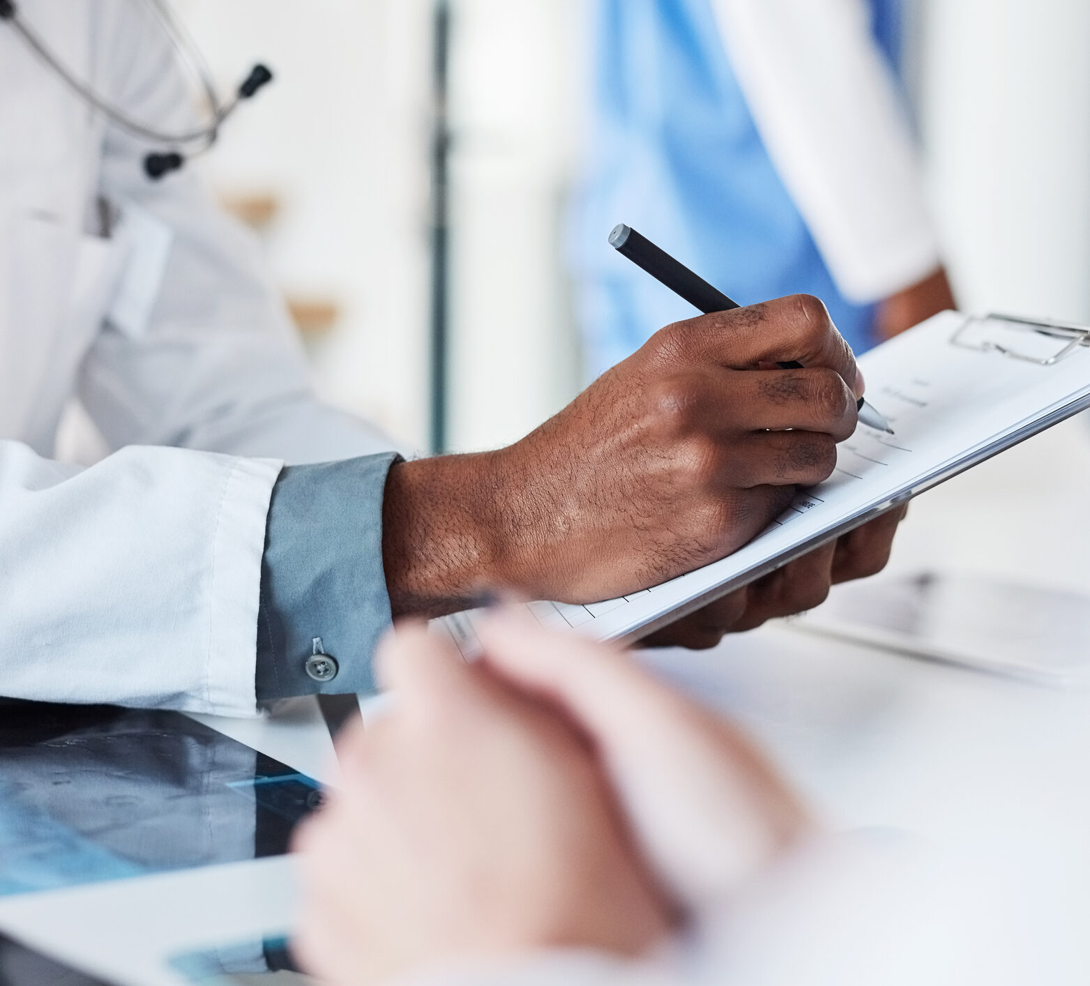 Closeup shot of an unrecognisable doctor writing on a clipboard in an hospital