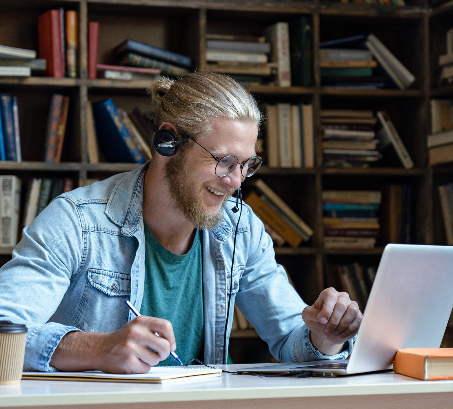 Smiling happy young man wear wireless headset look at laptop screen where he's watching trainings on time in range and CGM