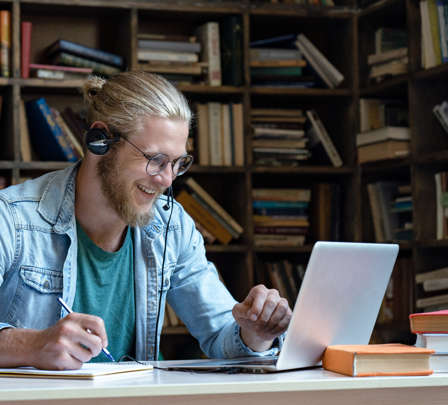 Smiling happy young man wear wireless headset look at laptop screen where he's watching trainings on time in range and CGM