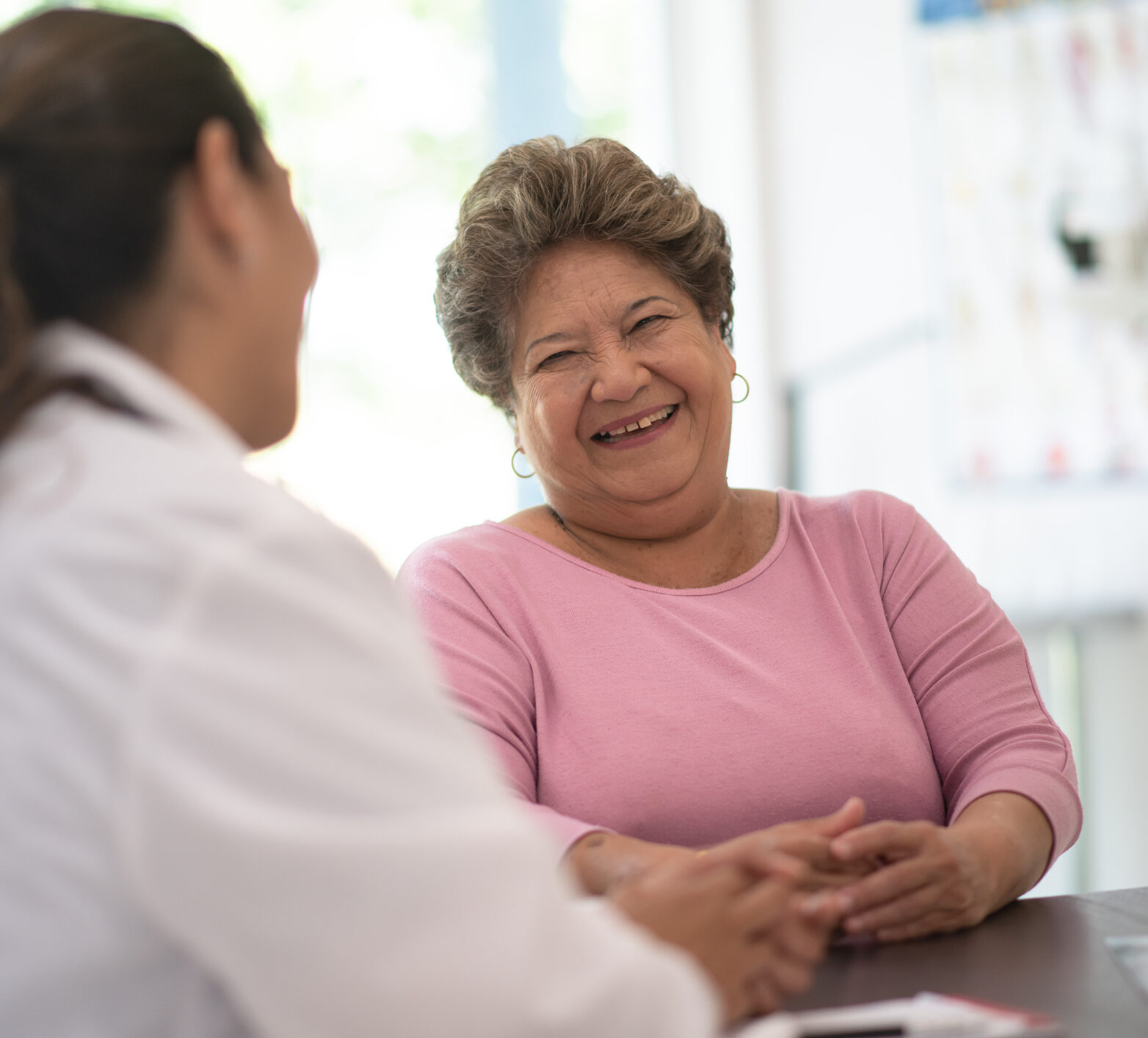 Woman in pink shirt happily talking to her HCP about time in range