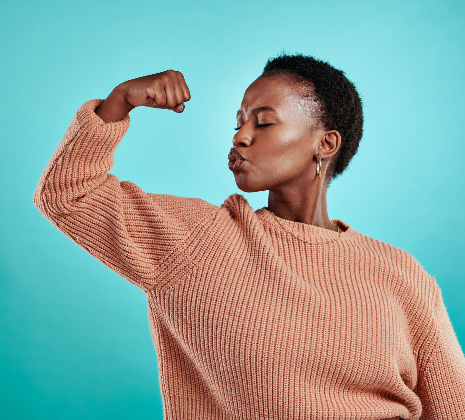 Woman with short hair flexing her am and kissing it—time in range makes her feel strong