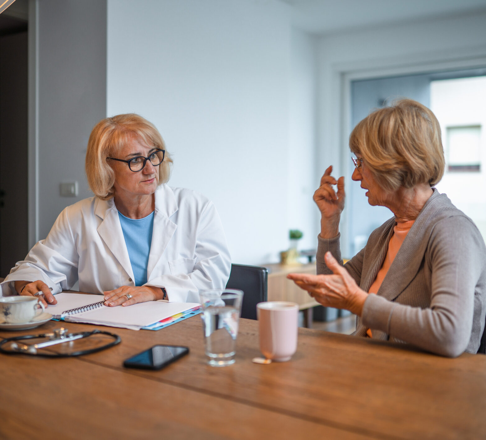 Blonde woman doctor talks to person with diabetes, a blonde woman with glasses, about time in range