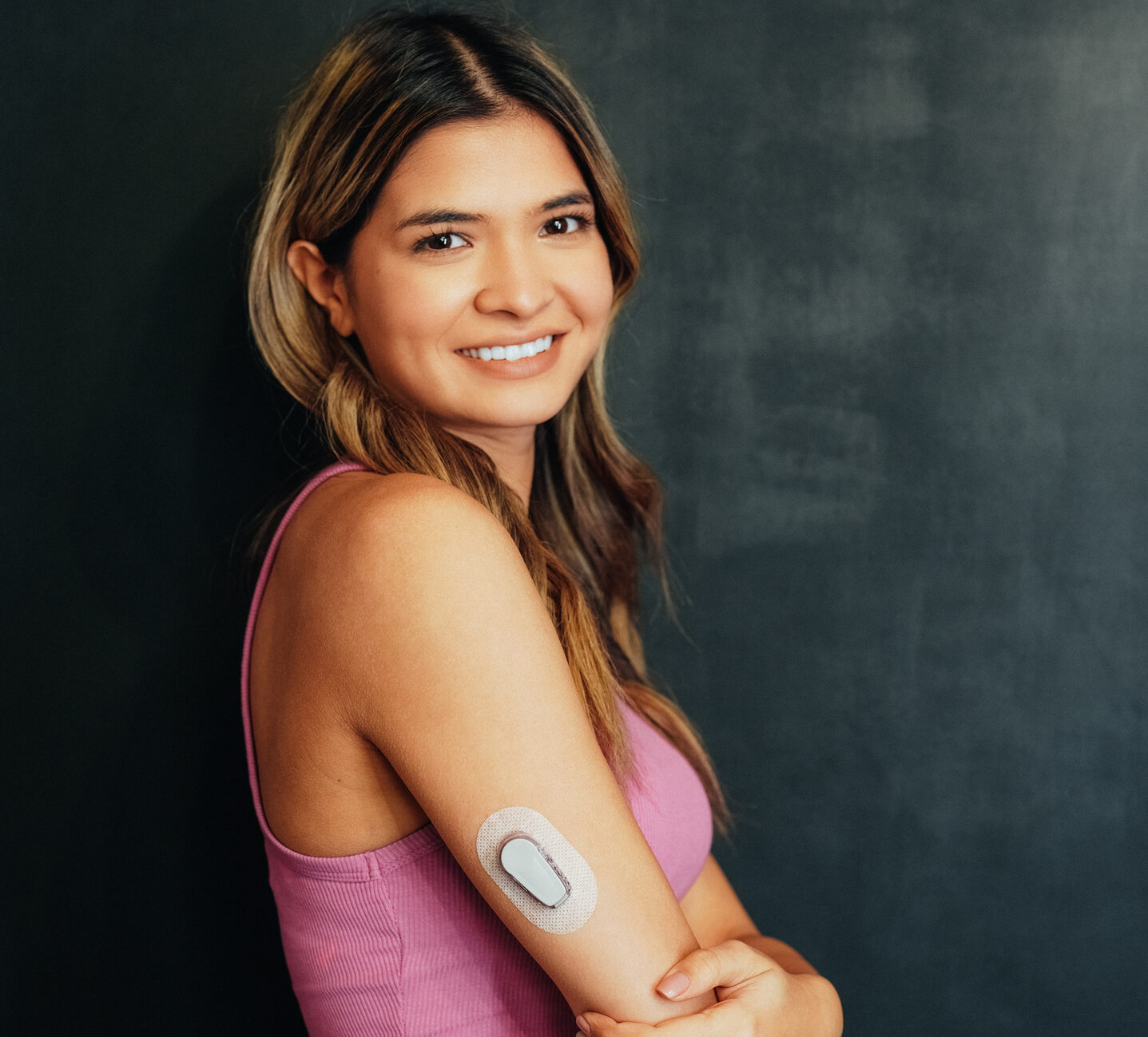 Woman with pink shirt with Dexcom G6 smiling