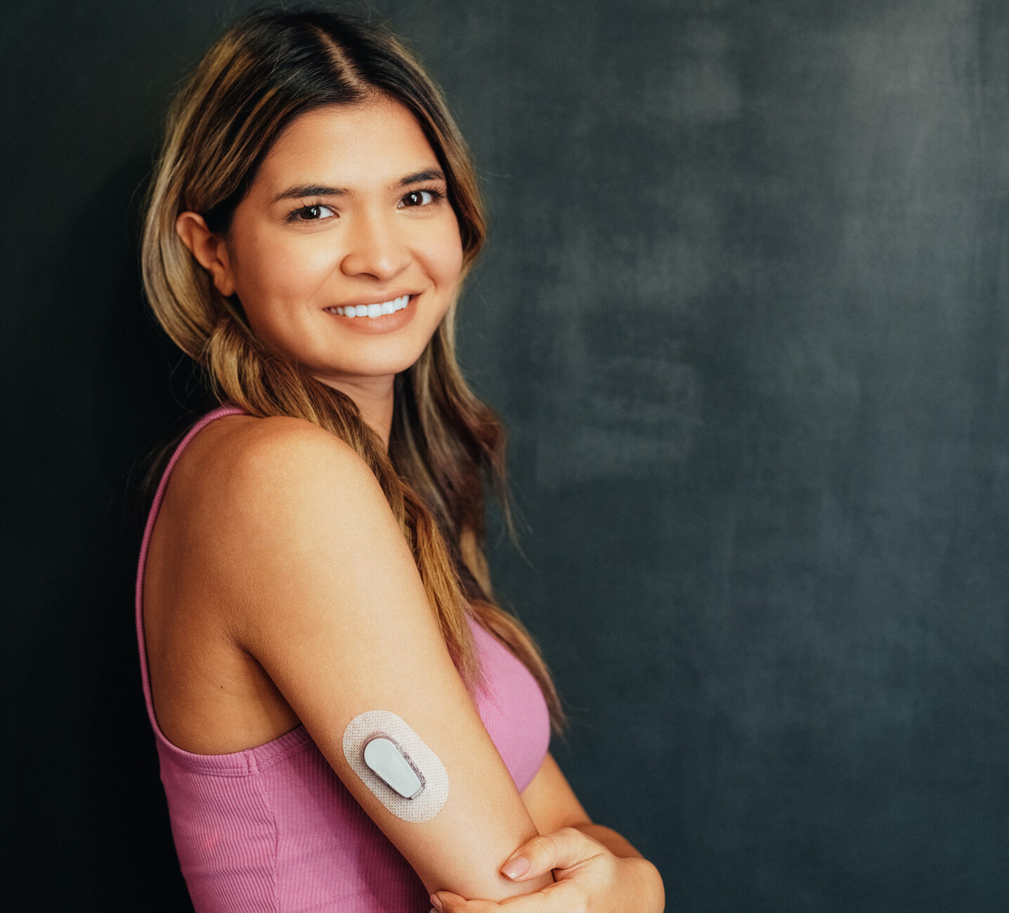 Woman with pink shirt with Dexcom G6 smiling