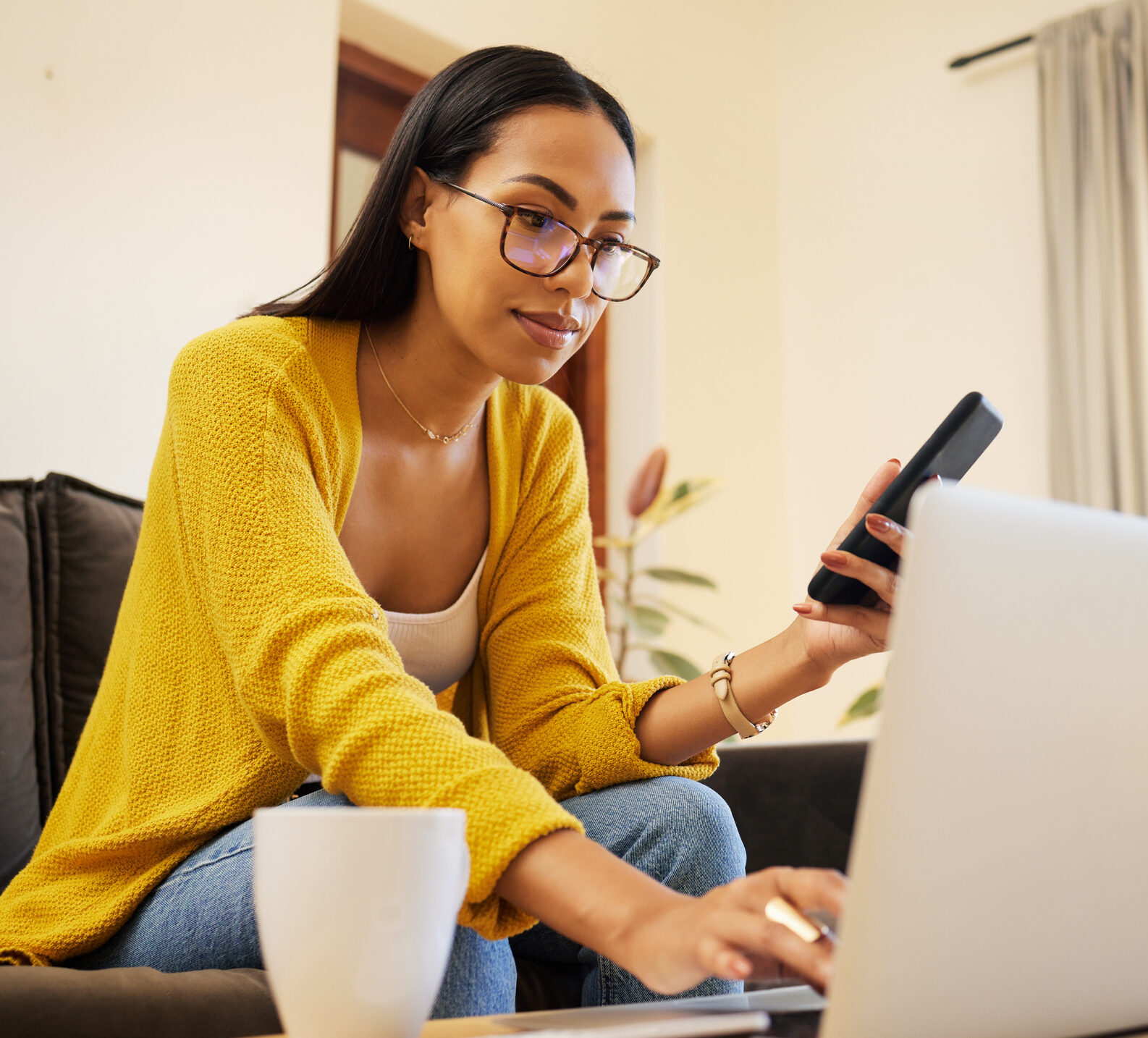 Woman in yellow cardigan looking intently at her computer to find CGM insurance information.