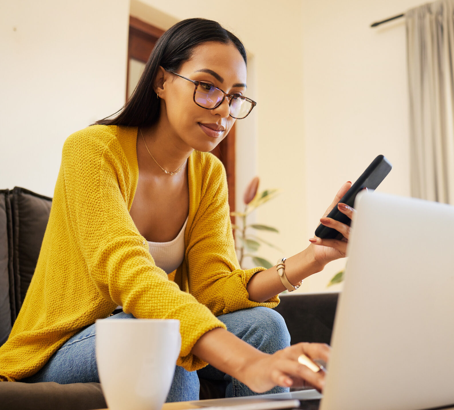 Woman in yellow cardigan looking intently at her computer to find CGM insurance information.