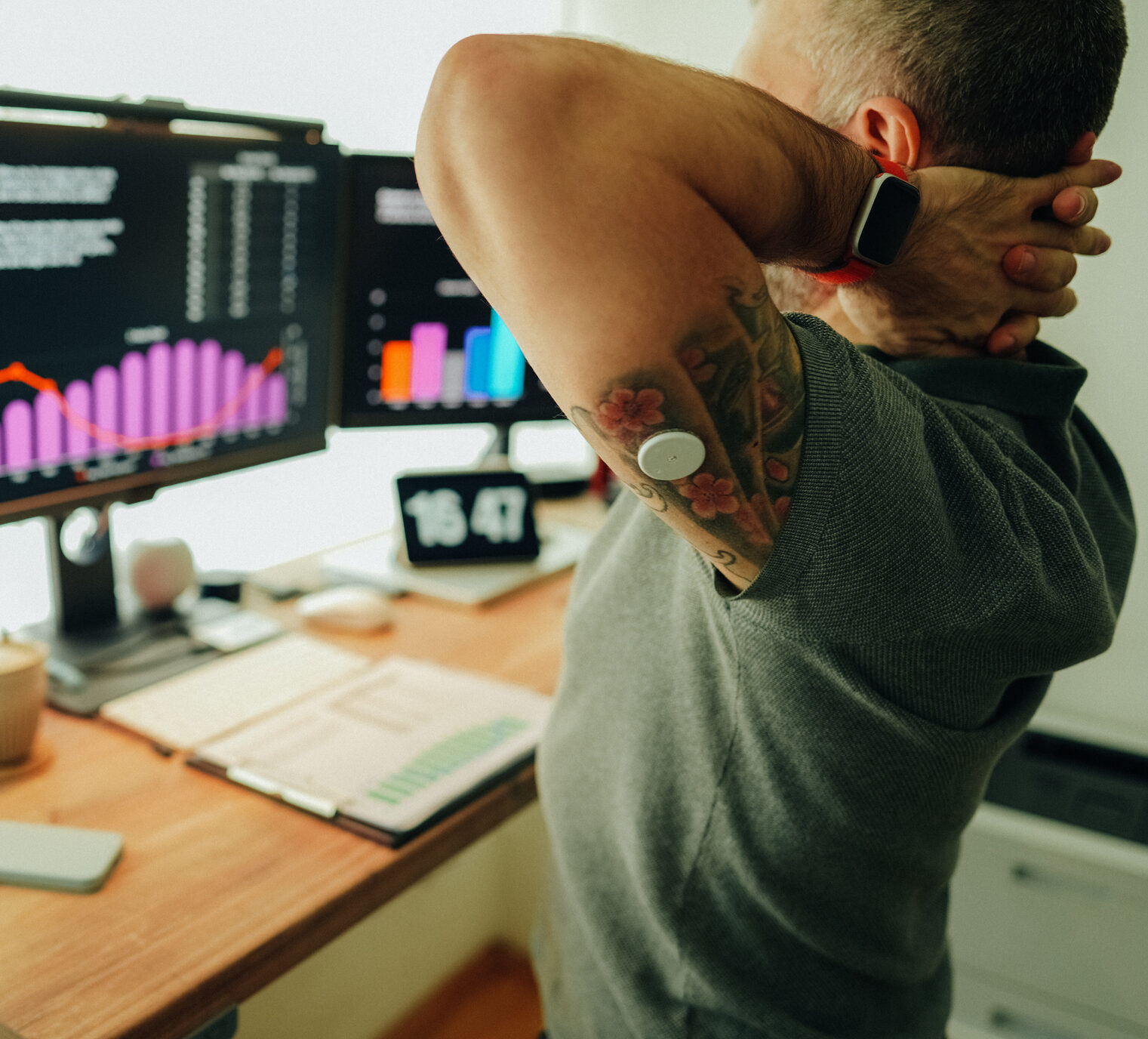 Man working remotely from home at standing desk, wearing a CGM to see his time in range