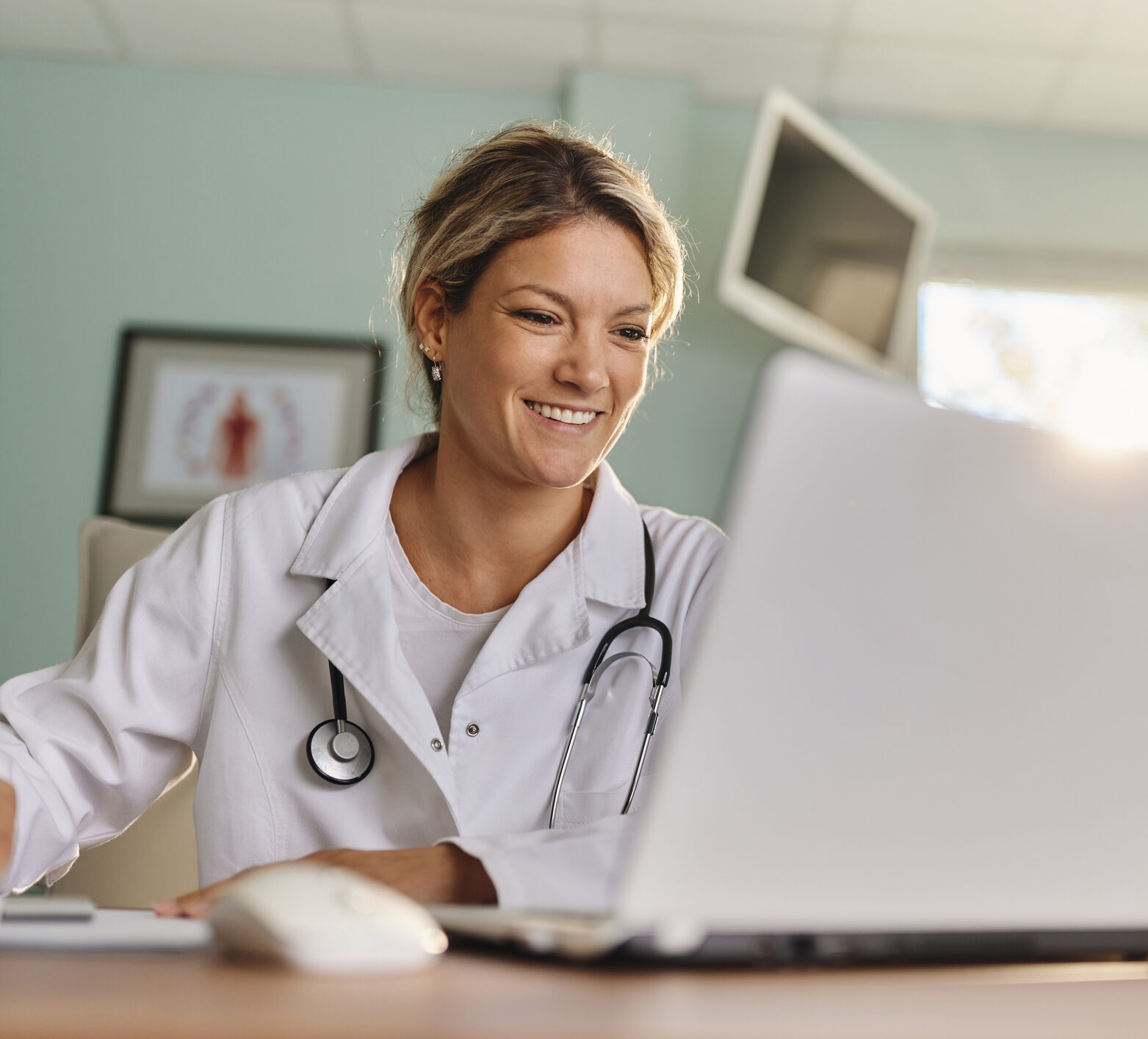 Happy medical expert reading an e-mail on a computer in the office at hospital, time in range in practice