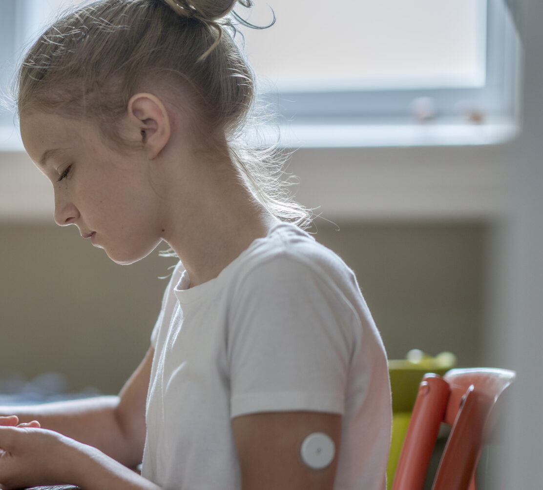 Young girl with freestlye Libre CGM on her am sitting at table