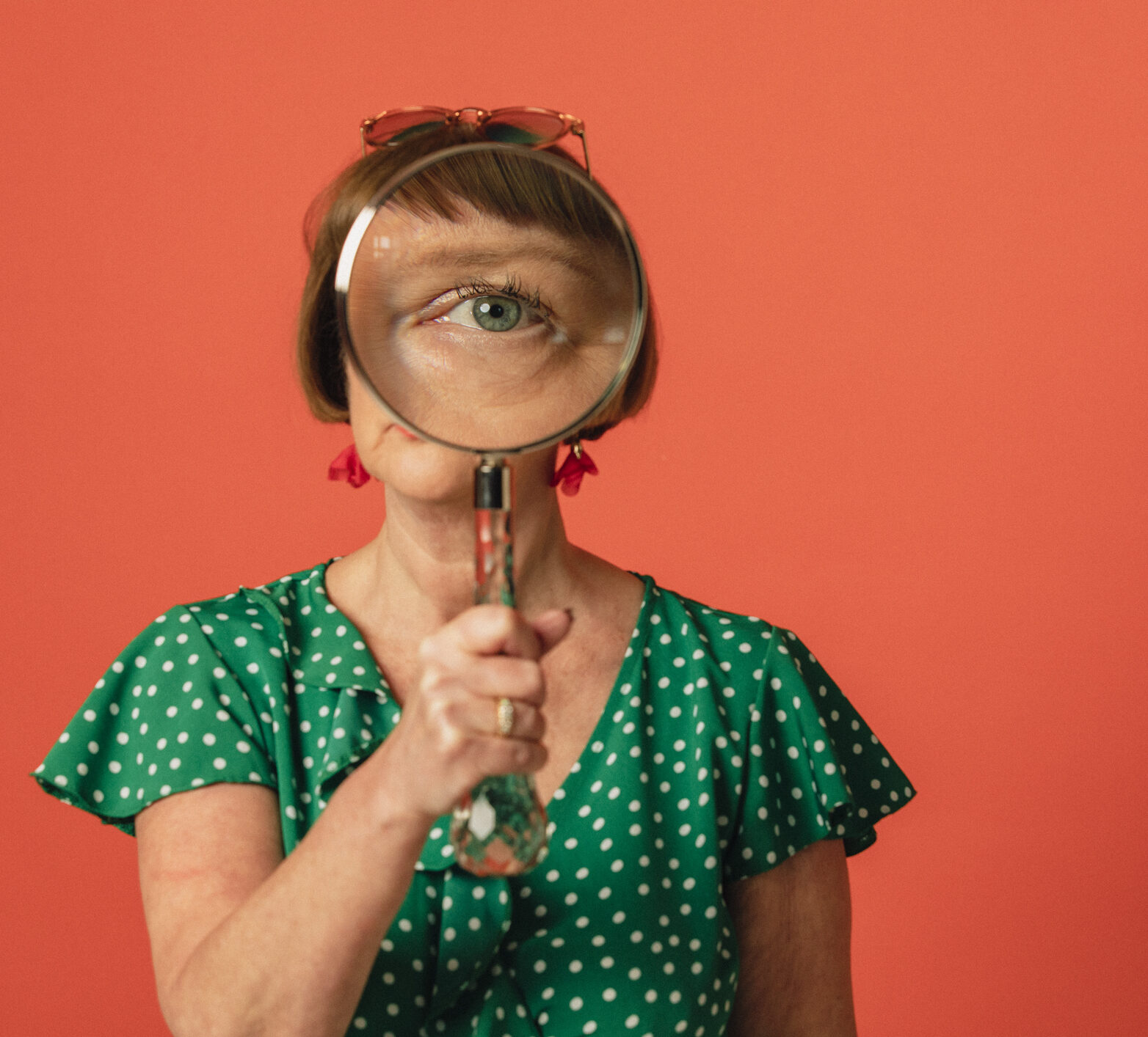 Woman in green shirt with magnifying glass over her eye